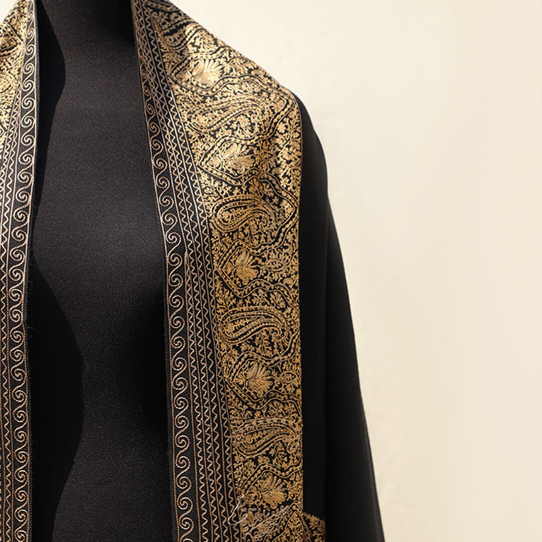 High quality pashmina wool shawl in Black pure wool base, with extensive border embroidery in golden color; fine machine-work with paisley p